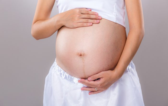 Belly of pregnant woman with gray background