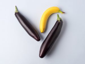 Eggplant and banana on gray background. Couple concept