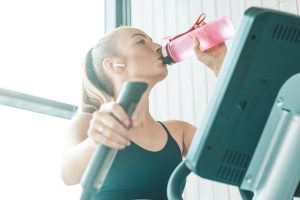 Hydrate yourself. Fitness girl in a gym sport club. Copy space on the left side