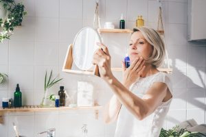 Beautiful middle aged woman taking care of her face
