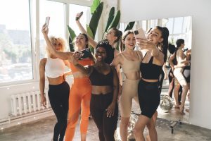 Group of multiethnic sportswomen taking selfie in gym
