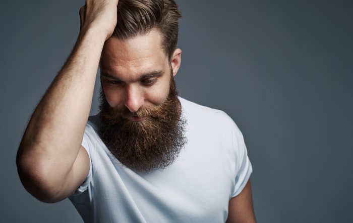 Thinking bearded man holding hair and laughing