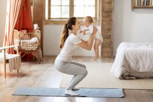 Young mom exercising with her infant son at home