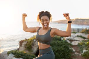 Glad strong excited millennial african american woman in sportswear doing success and victory gesture