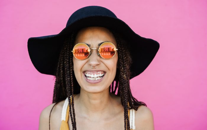 Hipster african girl smiling at camera outdoors with pink background Focus on face