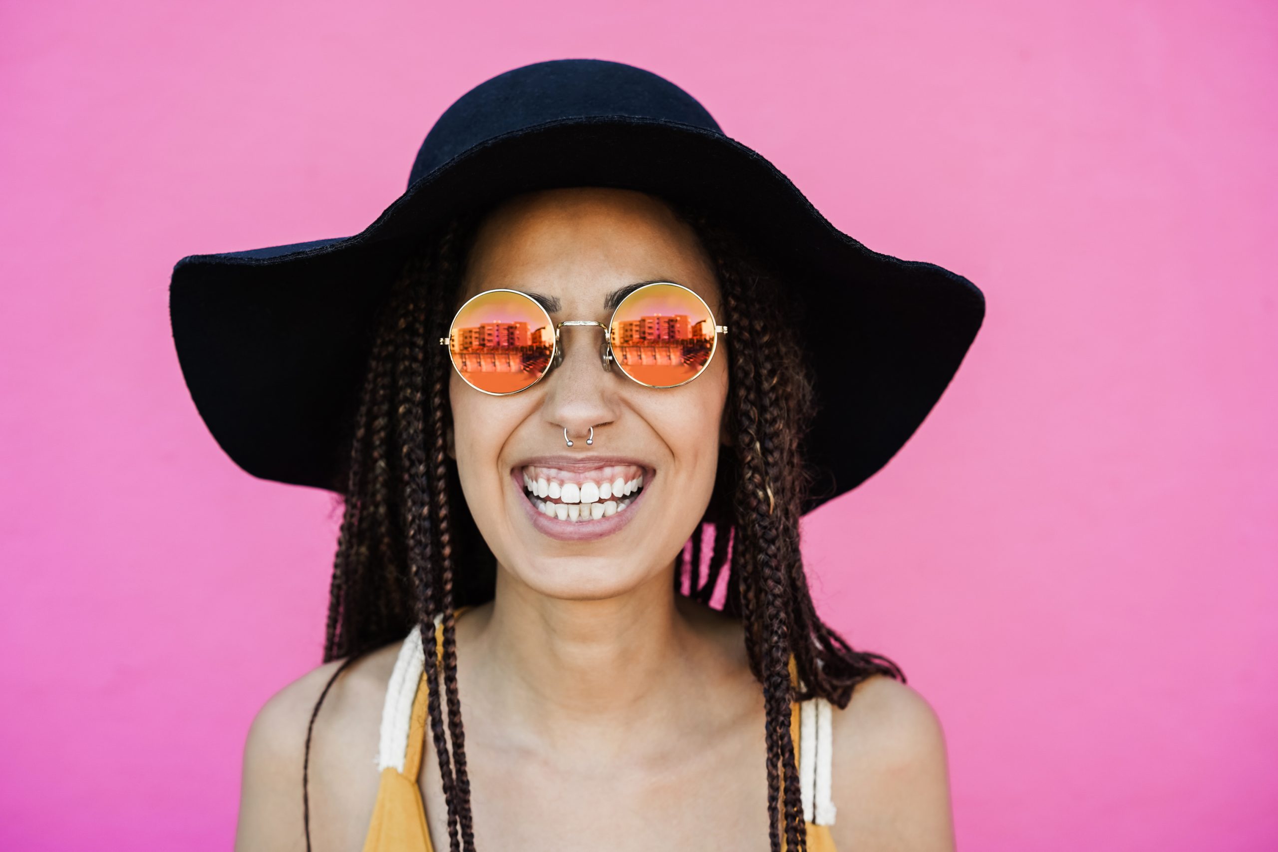 Hipster african girl smiling at camera outdoors with pink background Focus on face