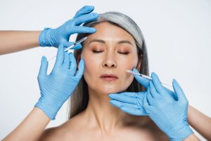 nude asian woman and doctors in latex gloves holding syringes with beauty injections isolated on