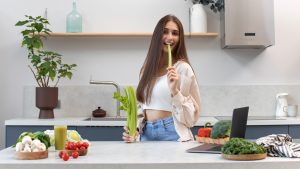 Attractive happy woman eating fresh celery. The concept of a healthy lifestyle, healthy nutrition