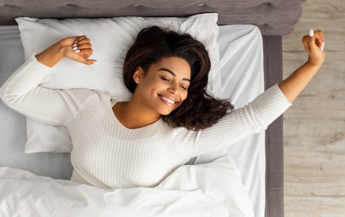 Satisfied young African American woman stretching after wake up